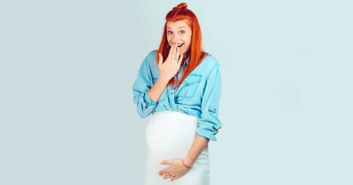 pregnant woman holidng her crotch with a hand over her mouth.