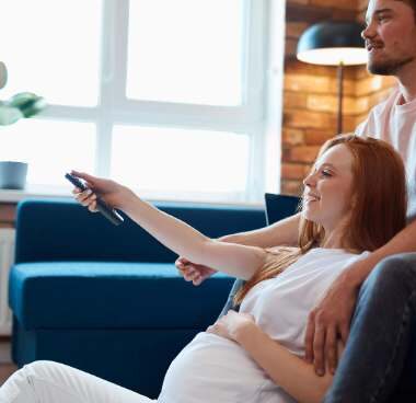 pregnant couple watching birth class on TV.