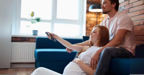 pregnant couple watching birth class on TV.