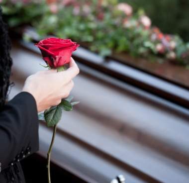 woman standing at a casket with a rose